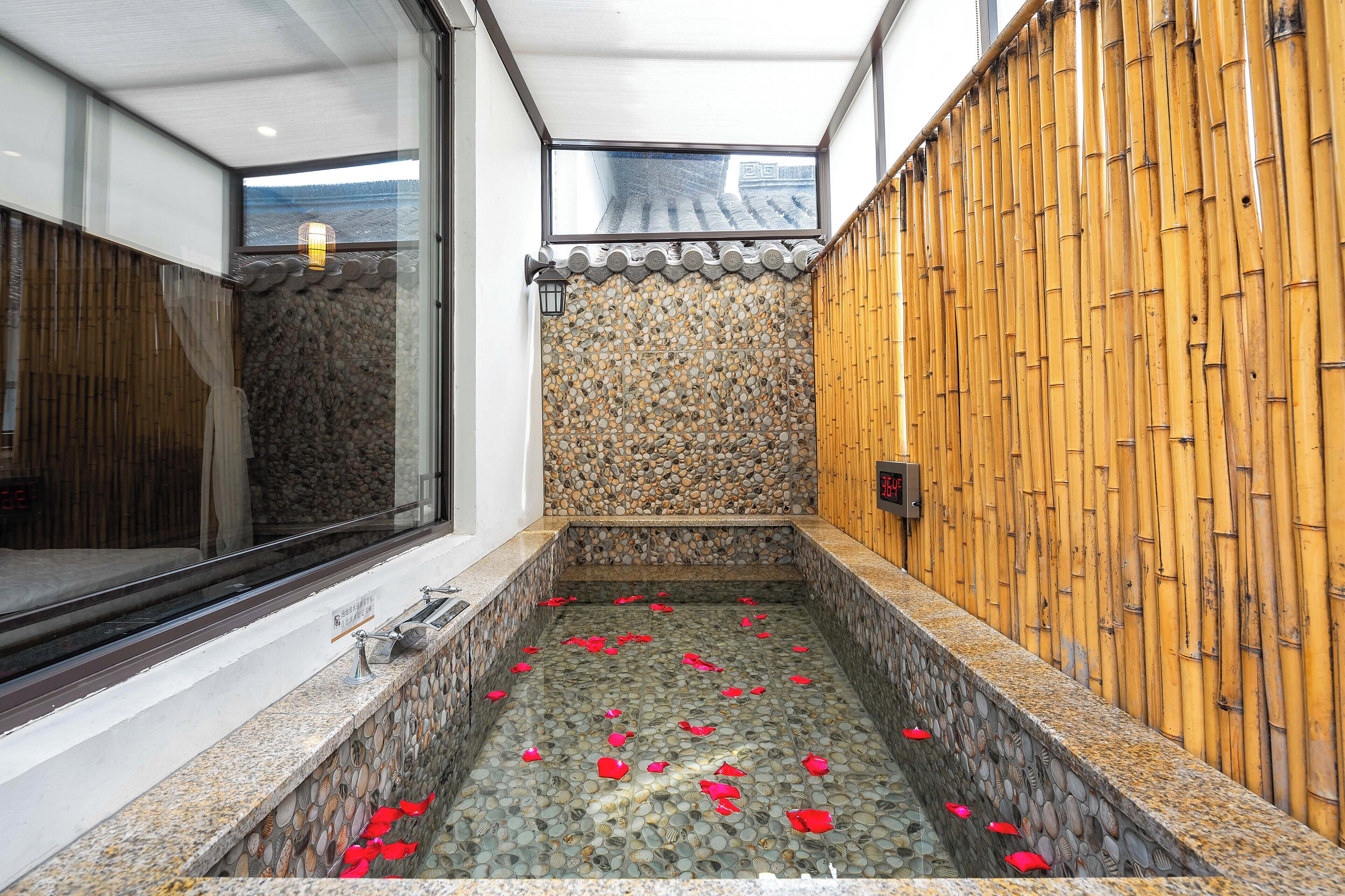 A spa area with a stone floor, a bamboo wall, and a window overlooking a building.