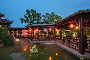 A traditional Chinese garden with a pond, wooden walkways, and lanterns. - nanjing youjianjiangnan Homestay (Nanjing)
