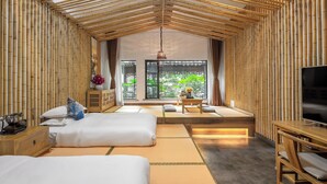 Una habitación con dos camas, televisión y vista a zonas verdes a través de amplios ventanales.