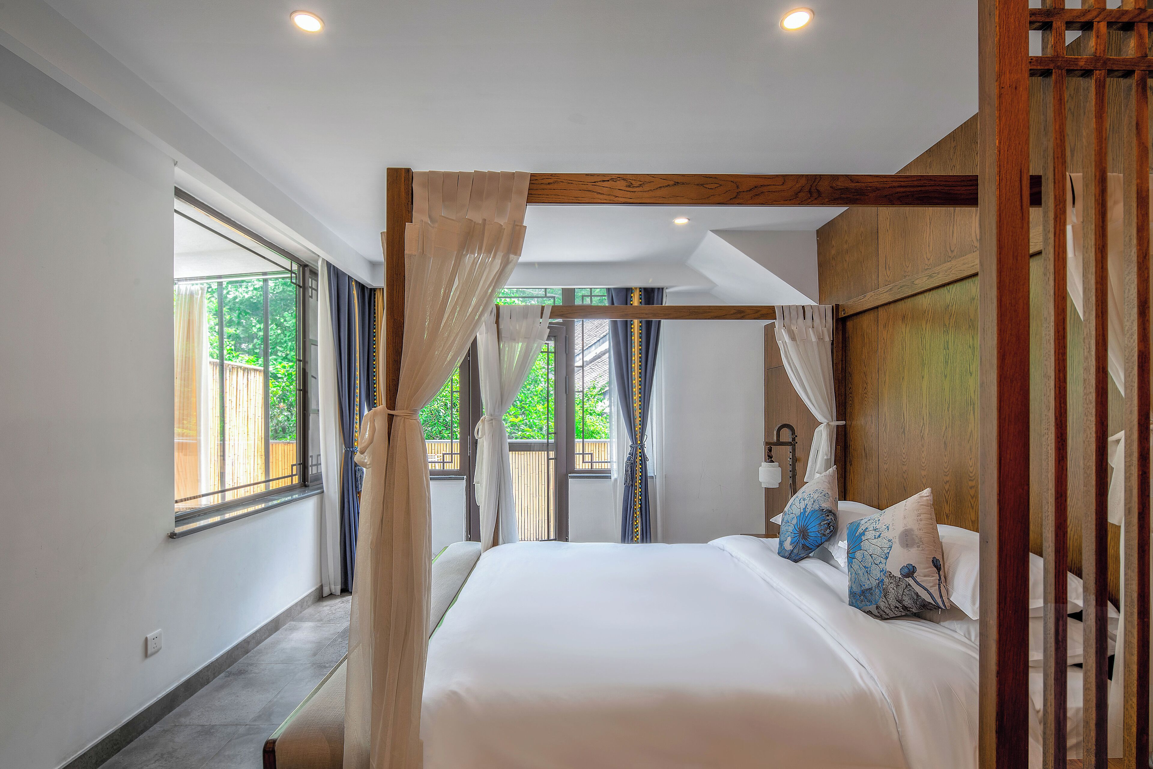 A bedroom with a large bed, a canopy, and a view of the outdoors.