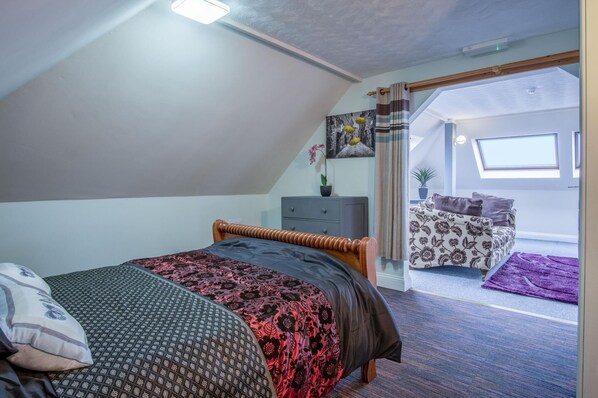 A bedroom with a bed, a nightstand, a window, and a view of the outside.