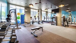 Een sportschool met diverse fitnessapparaten, grote ramen en een modern design.