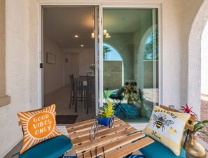 Une terrasse avec une table en bois, deux chaises et un vélo. Une porte-fenêtre coulissante donne accès à un espace de repas intérieur.