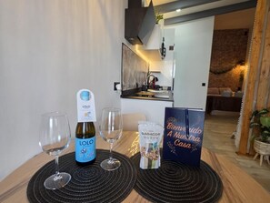 Une table avec une bouteille de vin Lolo, deux verres à vin, un sac de collations et un panneau d’accueil.