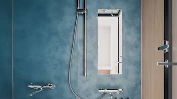 A modern bathroom with a large bathtub, a shower with a handheld hose, a wall-mounted mirror, and a small vanity with toiletries.