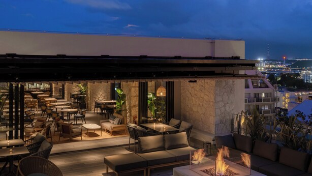 An outdoor terrace with seating and a fire feature, overlooking a cityscape at dusk. - THE NEST NAHA (Naha)