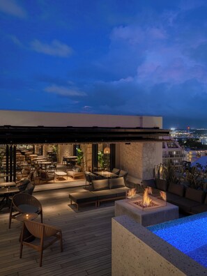 An outdoor terrace with seating and a fire feature, overlooking a cityscape at dusk. - THE NEST NAHA (Naha)