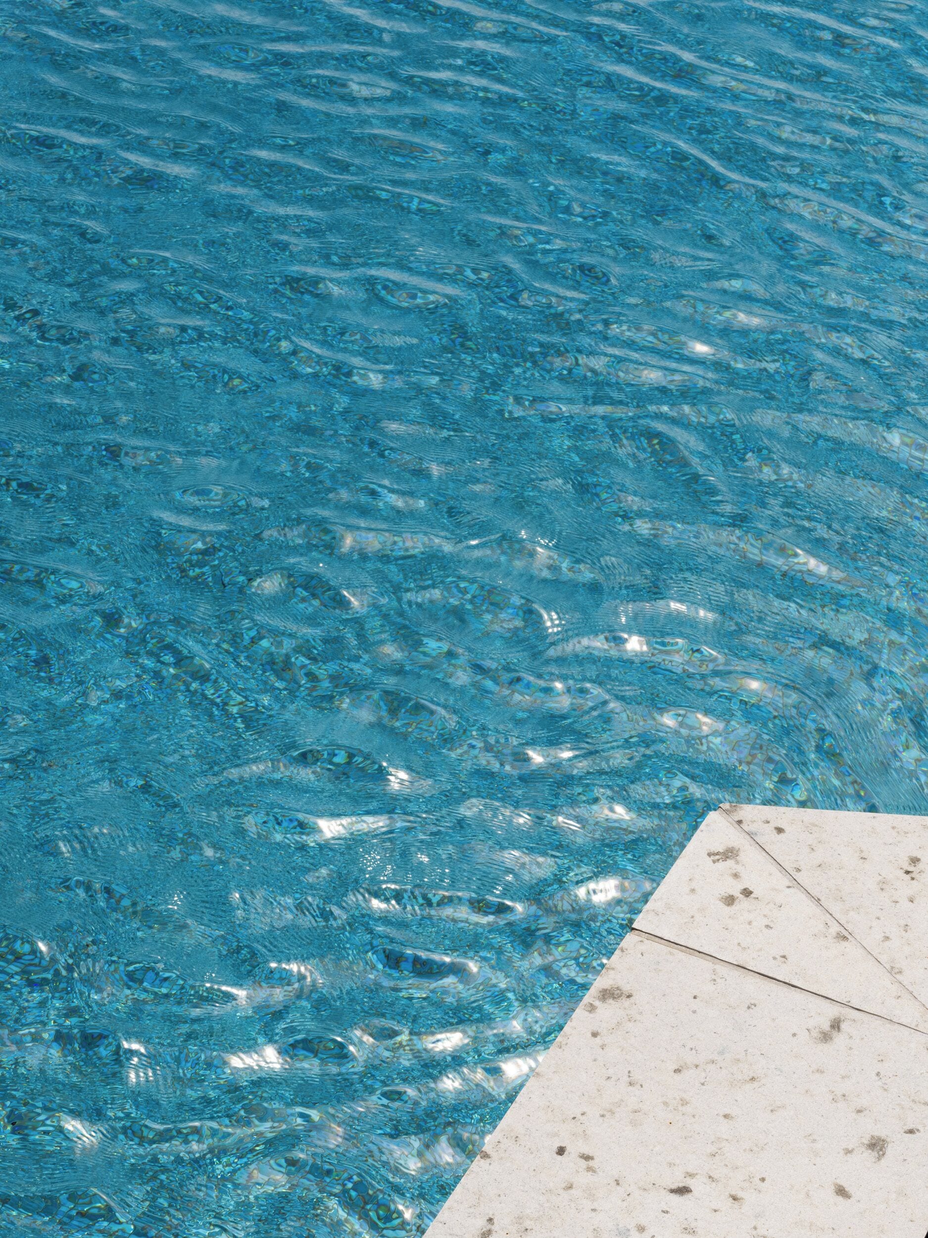 Una piscina con agua azul cristalina y borde de azulejos.