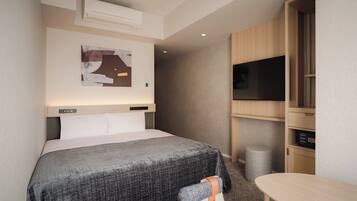 Una habitación de hotel moderna con una cama, un televisor, un escritorio y un aire acondicionado instalado en la pared.