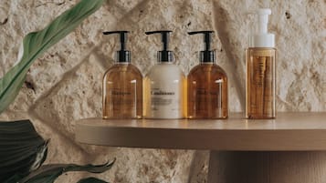 A shelf with four bottles of personal care products against a textured wall.