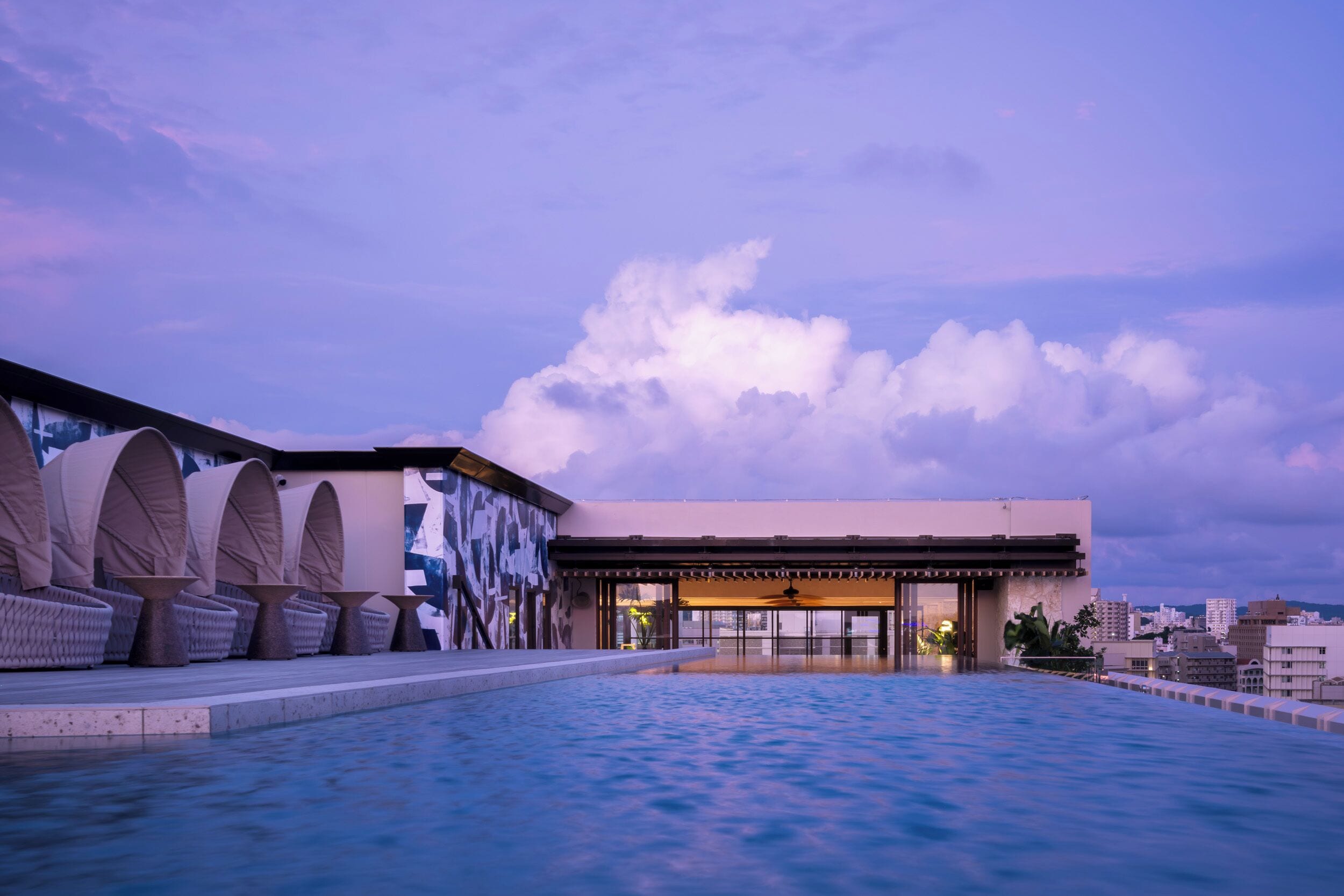 A rooftop pool area with lounge chairs and a building with large windows.