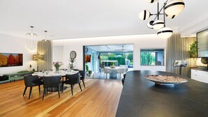 Une cuisine moderne dotée d’un îlot central, d’un coin repas avec des chaises et d’une vue sur le jardin.