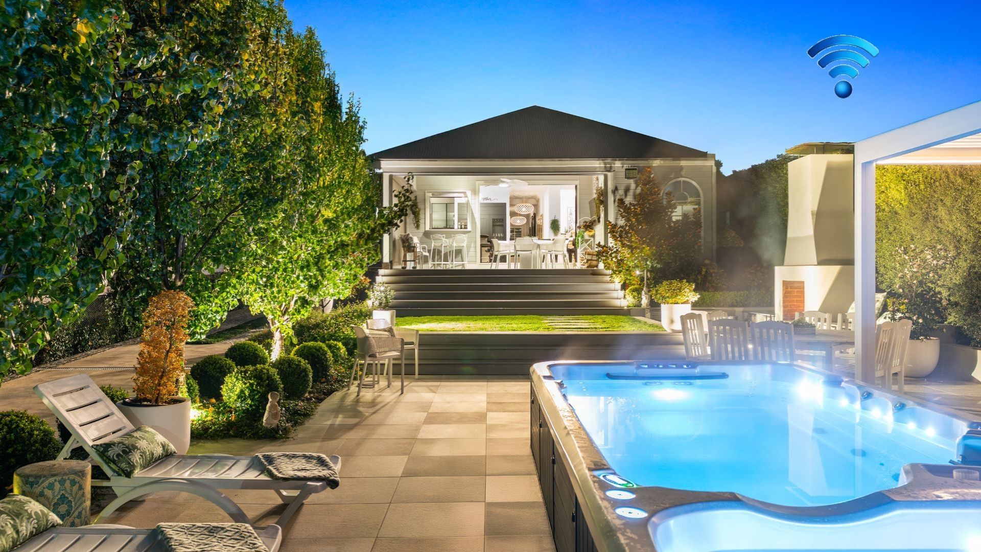 A modern outdoor pool area with lounge chairs, a hot tub, and a well-maintained garden.