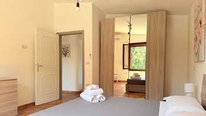 Ein geräumiges Schlafzimmer mit einem großen Bett, einer Holzkommode und Blick auf ein Badezimmer durch eine Tür.