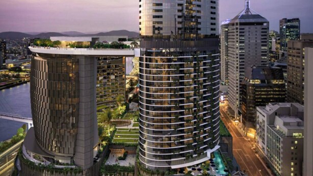 Un moderno edificio de gran altura con fachada curva, rodeado de otros edificios y un río.