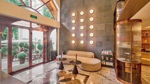 A spacious lobby with a large chandelier, a seating area, and a view of the outdoors.