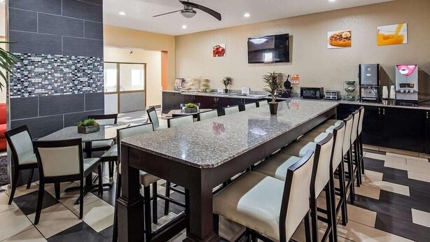 A modern kitchen with a long island, bar stools, and a flat-screen TV. - Red Lion Inn & Suites Blue Springs (Blue Springs)