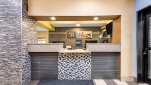 A reception area with a check-in counter, a tiled mosaic wall, and a sign for Red Lion Inn Suites. - Red Lion Inn & Suites Blue Springs (Blue Springs)