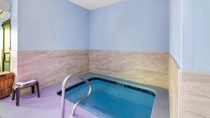 A modern bathroom with a built-in bathtub, a small stool, and a wicker basket. - Red Lion Inn & Suites Blue Springs (Blue Springs)
