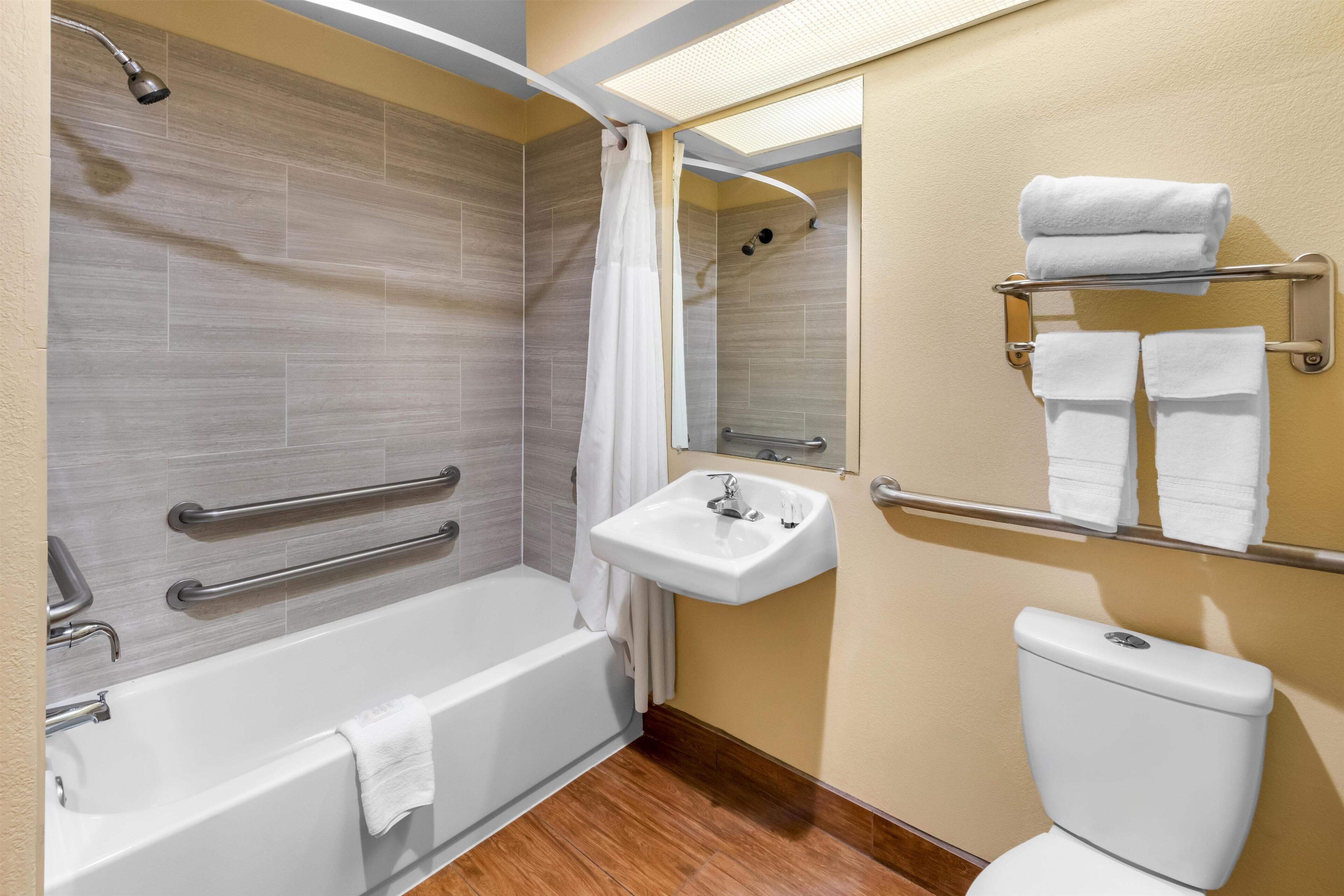 A modern bathroom with a bathtub, shower, sink, and toilet.