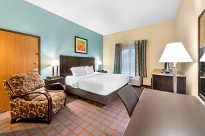 A hotel room with a bed, a chair, a desk, and a nightstand.