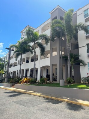 Een hotel met meerdere verdiepingen, balkons en palmbomen.