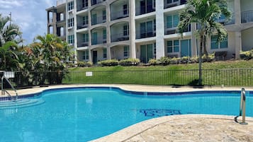 Enjoy a refreshing dip in the pool surrounded by lush greenery and palm trees.