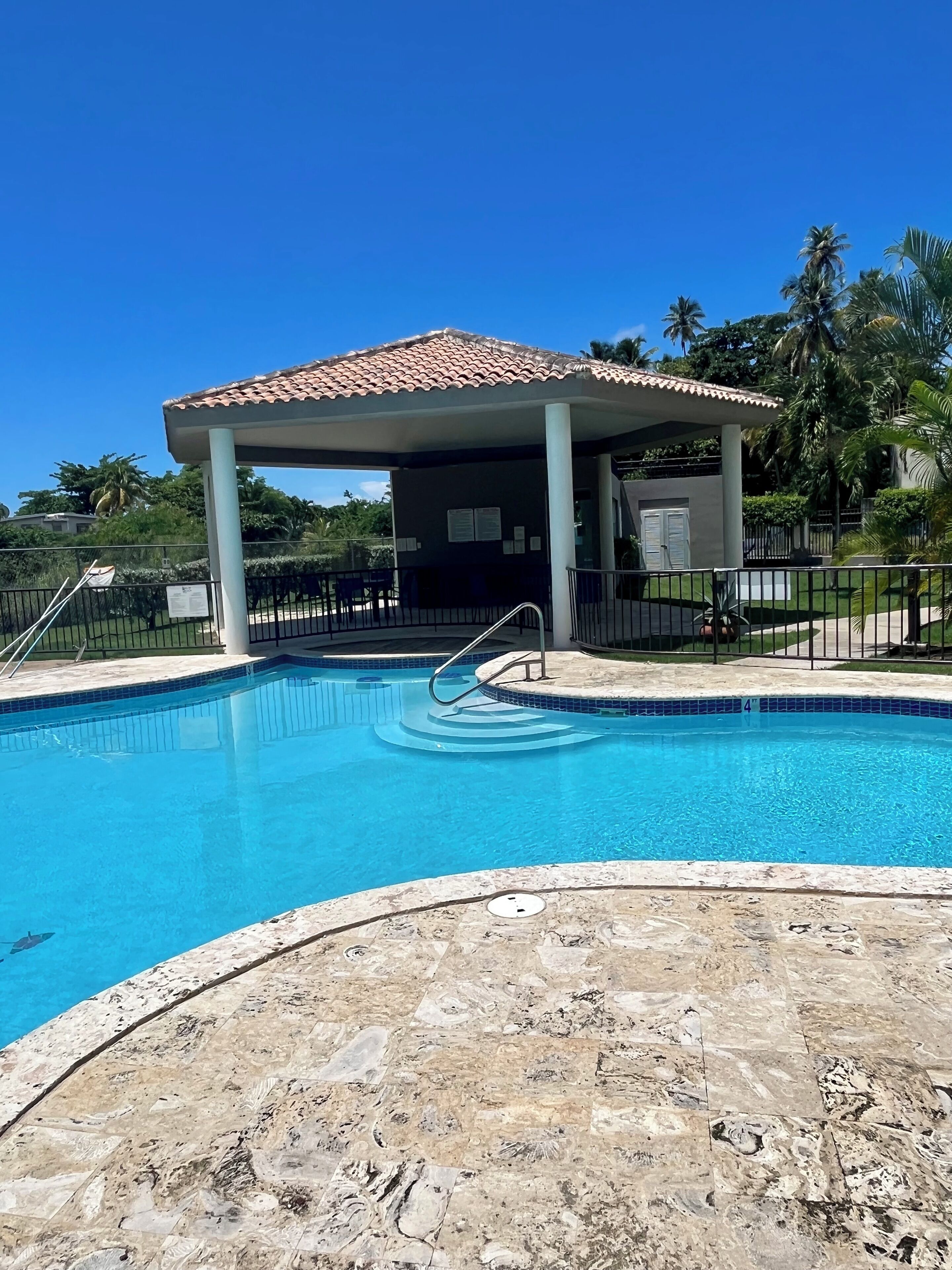 A swimming pool with a tiled deck area and a covered pavilion.