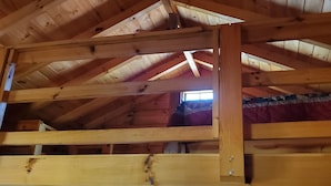 A wooden interior with a sloped ceiling, visible beams, and a window allowing natural light.