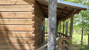 A wooden cabin with a porch and a staircase leading up to it.