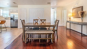 Una cocina moderna con suelo de madera, una mesa de comedor con sillas y una isla de cocina con lámpara.