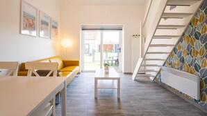 Un intérieur moderne avec un escalier, un canapé, une table et une vue à travers une porte vitrée.