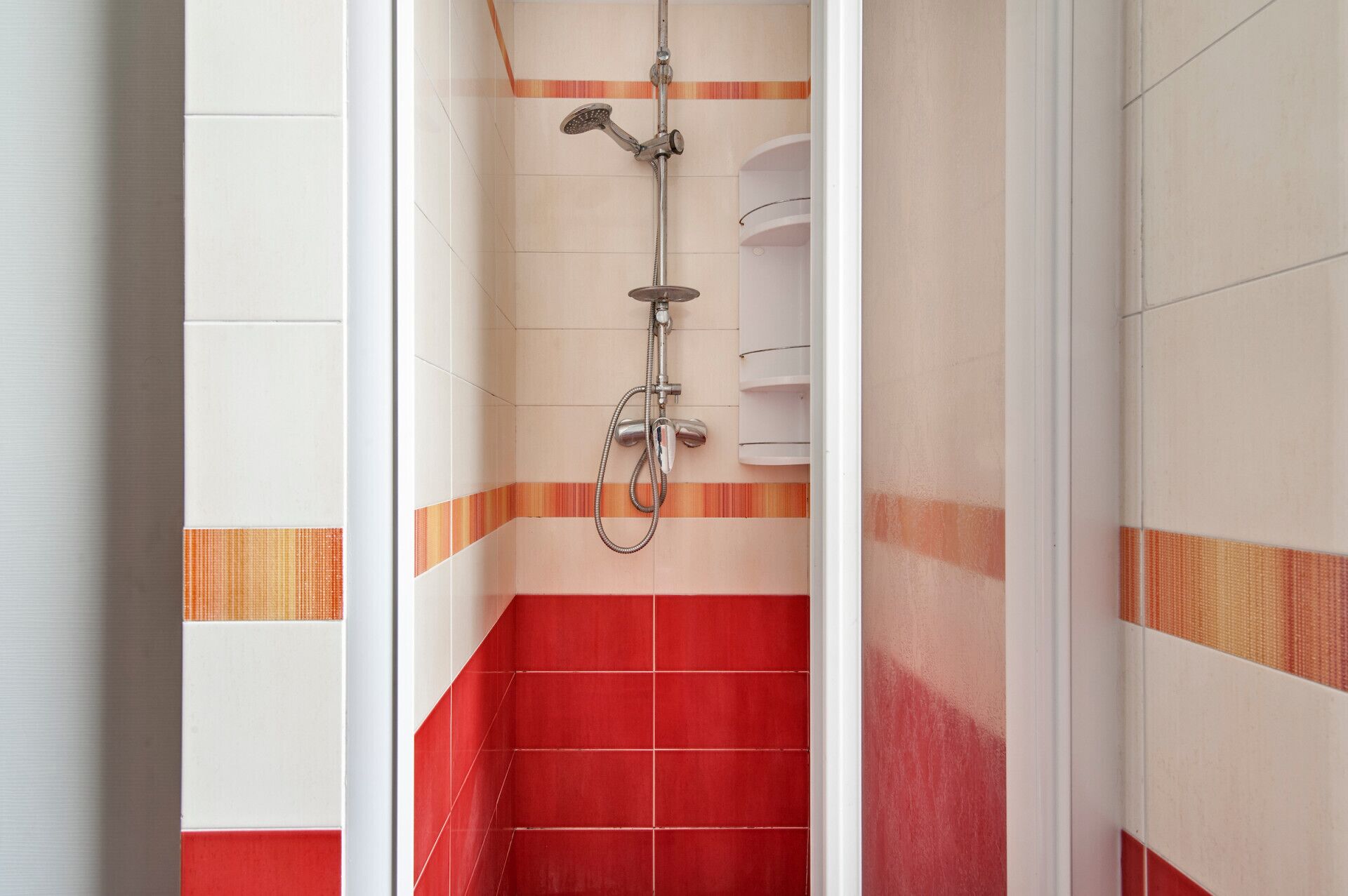 Ein Badezimmer mit Dusche, gefliesten Wänden und einem roten Fliesenboden.