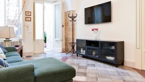 A living room with a sofa, a TV mounted on the wall, and a cabinet with glass doors. - Fanfulla Court - Lecce Selection (Lecce)