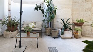 A cozy indoor patio with a cushioned seating area, various potted plants, and a metal table. - Fanfulla Court - Lecce Selection (Lecce)