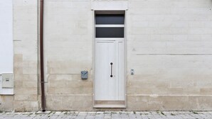 A white door with a small window above it, set in a beige brick wall. - Arco Barocco - Lecce Selection (Lecce)