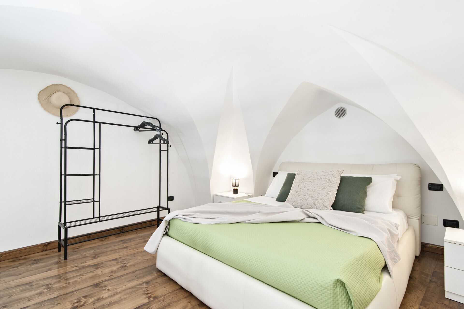 Una camera da letto con un letto a castello, una scala in metallo, un comodino e un appendiabiti a parete.