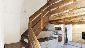 A kitchen with a wooden staircase, a gas stove, and a stone wall. - Baglivi 17 - Lecce Selection (Lecce)