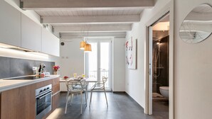 Una cocina moderna con encimera de madera, un comedor con mesa y sillas, y un baño con ducha.