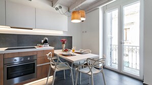 Una cocina moderna con encimera de madera, electrodomésticos de acero inoxidable y un comedor con sillas blancas y una mesa.