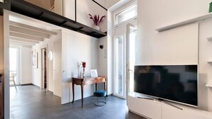 Una sala de estar moderna con un televisor de pantalla plana grande, una mesa de centro de madera y un otoman azul.