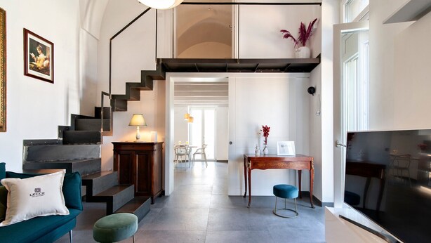 Una sala de estar moderna con una escalera, un sofá, una mesa de centro y un televisor.