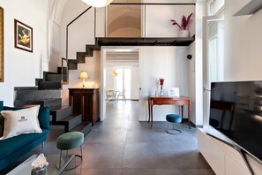A modern living room with a staircase, a sofa, a coffee table, and a TV. - Dimora del Duca - Lecce Selection (Lecce)