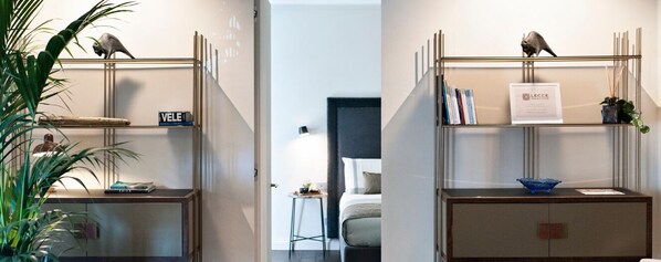Ein Hotelzimmer mit Bett, Nachttisch, einer Ablage mit Dekoration und einer Wandablage mit einem Schild.