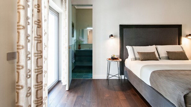A bedroom with a bed, bedside table, and a view of a bathroom. - HON Lecce Hospitality - Lecce Selection (Lecce)