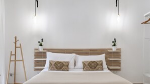 A neatly arranged bedroom with a wooden headboard, two bedside tables with potted plants, a wooden ladder, and a large bed with a beige blanket. - InCentro Central Suite - Lecce Selection (Lecce)