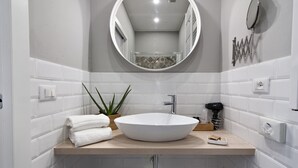 A modern bathroom with a large oval sink, a round mirror, and a potted aloe vera plant. - InCentro Central Suite - Lecce Selection (Lecce)