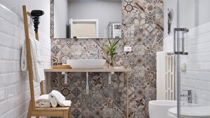 A modern bathroom with a white sink, a small table with a plant, and a towel rack. - InCentro Family Suite - Lecce Selection (Lecce)