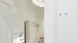 A white room with a bed, a chair, and a sign indicating the Garden Suite.