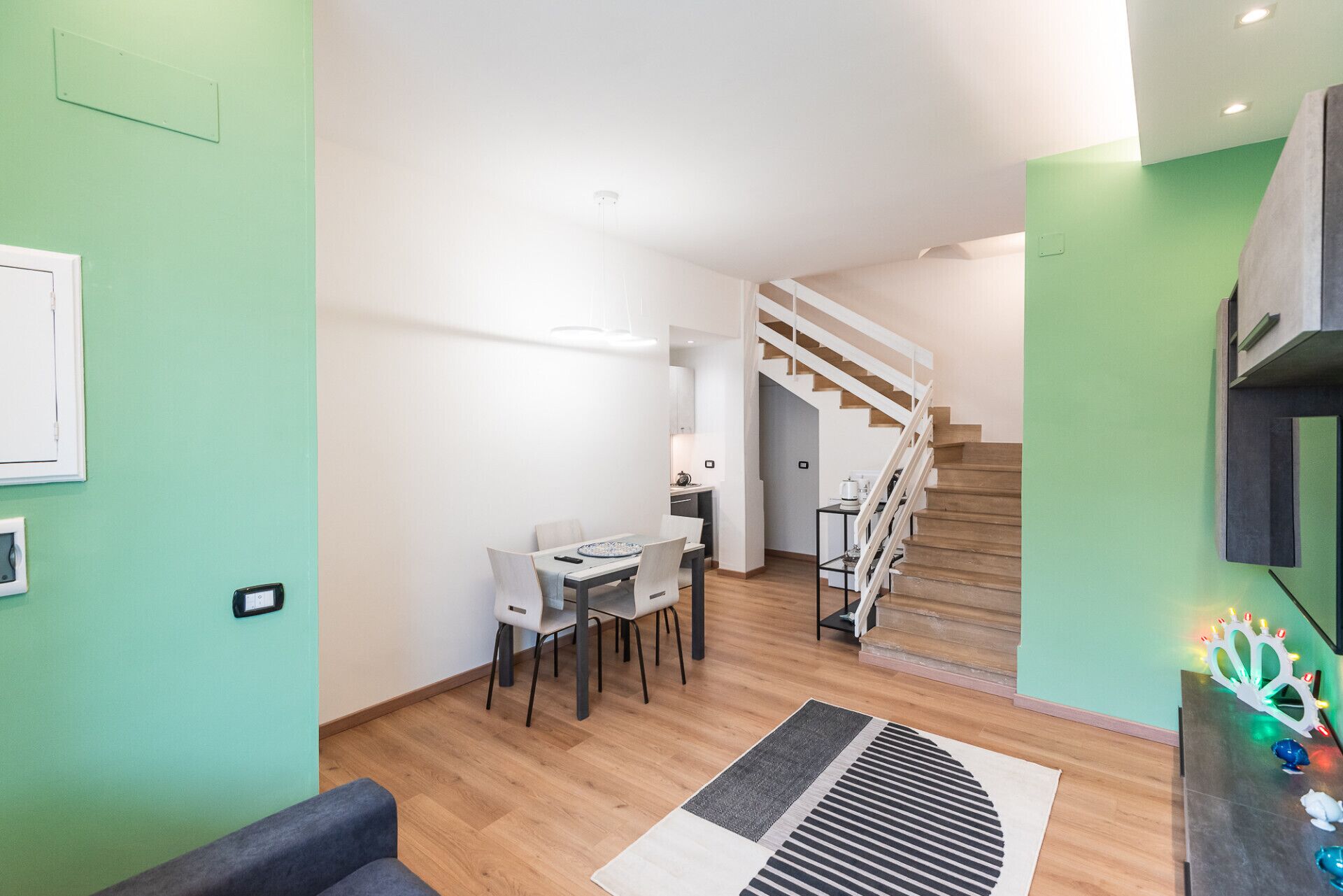 Un apartamento moderno con comedor, cocina y escalera.